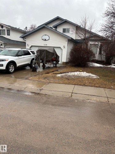 Two-story residence featuring white horizontal siding, an attached two-car garage with a basketball hoop, a paved driveway, and mature landscaping - 5306 44 Street, Cold Lake, AB - Outdoor
