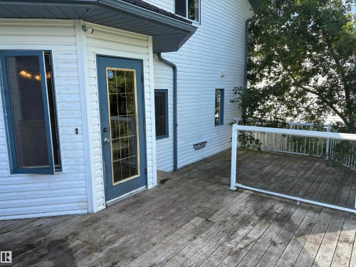 Expansive outdoor deck with white railing, featuring a glass-paneled door and light-colored siding - 5306 44 Street, Cold Lake, AB - Outdoor With Exterior