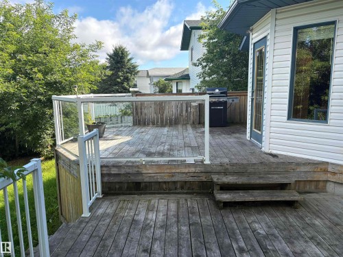 Multi-level deck with glass panel railing and wood fencing, featuring a single entry door with an adjacent vertical window - 5306 44 Street, Cold Lake, AB - Outdoor With Deck Patio Veranda With Exterior