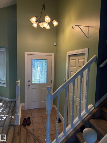 Foyer featuring a decorative chandelier, tile flooring, and a white entry door with a leaded glass insert - 5306 44 Street, Cold Lake, AB - Indoor Photo Showing Other Room