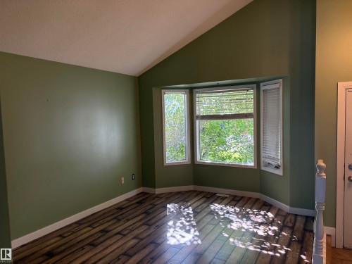 Wood-finish flooring with a bay window, vaulted ceiling, and painted walls - 5306 44 Street, Cold Lake, AB - Indoor Photo Showing Other Room