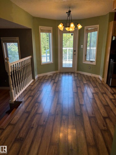 Wood-finish flooring throughout, bay windows with white trim, and a patio door with integrated grids - 5306 44 Street, Cold Lake, AB - Indoor Photo Showing Other Room