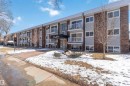 The property features a multi-story building facade with brick and horizontal siding accents, multiple balconies with white railings, and a main entrance with an awning - 111 10225 117 Street, Edmonton, AB 