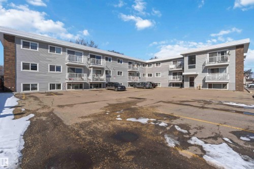 The property features a multi-story building with gray siding and white-framed windows - 111 10225 117 Street, Edmonton, AB 