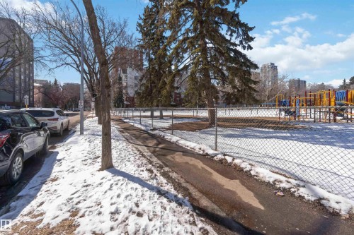 The property is located near a park featuring a playground and mature trees - 111 10225 117 Street, Edmonton, AB 