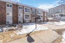 The property features a brick exterior with light-colored siding, balconies with white railings, and a paved entryway - 111 10225 117 Street, Edmonton, AB 