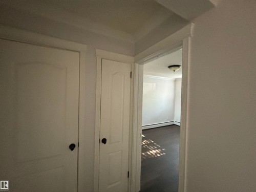 White interior doors with dark hardware, crown molding, and wood-finish flooring - 111 10225 117 Street, Edmonton, AB 