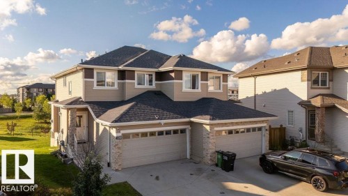 Duplex exterior featuring light-colored siding, contrasting dark trim, and stone accents - 6708 Cardinal Road, Edmonton, AB - Outdoor