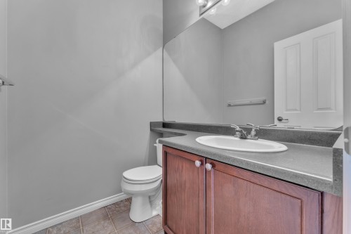 Bathroom featuring a built-in wood-finish vanity with a single basin sink and dark countertop - 110 13825 155, Edmonton, AB - Indoor Photo Showing Bathroom