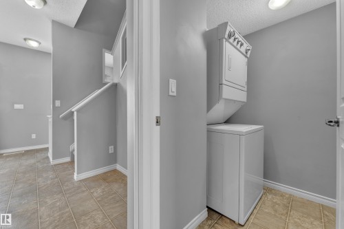 Dedicated laundry area featuring a stacked washer and dryer unit - 110 13825 155, Edmonton, AB - Indoor Photo Showing Laundry Room