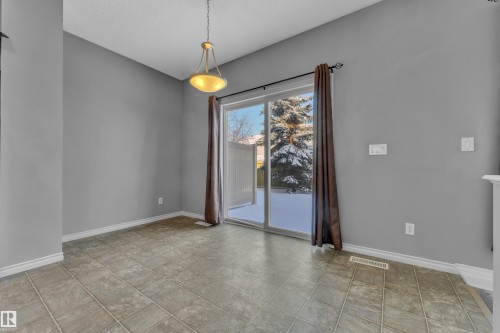 Dining area featuring a contemporary chandelier, sliding glass patio door, and tiled flooring - 110 13825 155, Edmonton, AB - Indoor Photo Showing Other Room