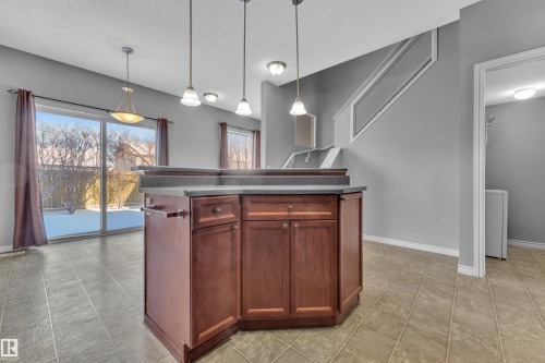 Central kitchen island featuring wood-finish cabinetry and a dark countertop - 110 13825 155, Edmonton, AB - Indoor Photo Showing Other Room