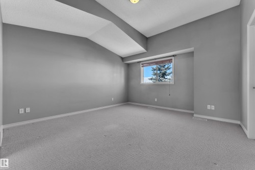 Spacious room featuring light gray carpet flooring, neutral gray wall paint, and a textured white ceiling - 110 13825 155, Edmonton, AB - Indoor Photo Showing Other Room