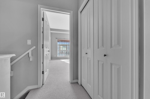 Carpeted hallway with light gray walls, white baseboards, and a white handrail - 110 13825 155, Edmonton, AB - Indoor Photo Showing Other Room