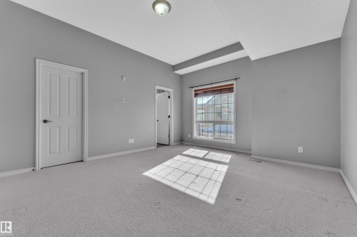 Spacious room featuring light gray carpeting and matching wall paint - 110 13825 155, Edmonton, AB - Indoor Photo Showing Other Room