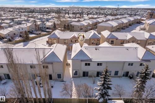 Townhome exterior featuring multiple window placements, a pitched roofline, and a private rear yard with mature evergreens - 110 13825 155, Edmonton, AB - Outdoor