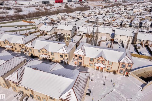 Residential property featuring a light-colored stucco exterior with red trim accents and a multi-level roofline - 110 13825 155, Edmonton, AB - Outdoor