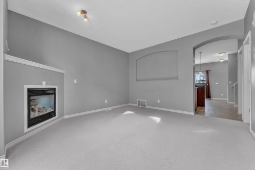 Living area featuring an inset fireplace with a white trim surround, light-toned carpeting, and track lighting - 110 13825 155, Edmonton, AB - Indoor With Fireplace