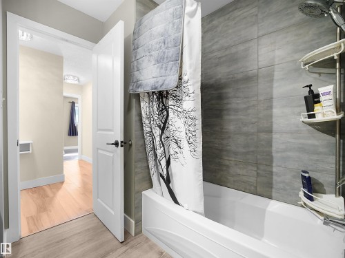 White bathtub with a gray tiled shower surround - 11044 166 Avenue, Edmonton, AB - Indoor Photo Showing Bathroom