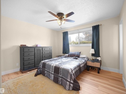Bedroom featuring wood-finish flooring, a ceiling fan with integrated lighting, and a window with dark drapery - 11044 166 Avenue, Edmonton, AB - Indoor Photo Showing Bedroom