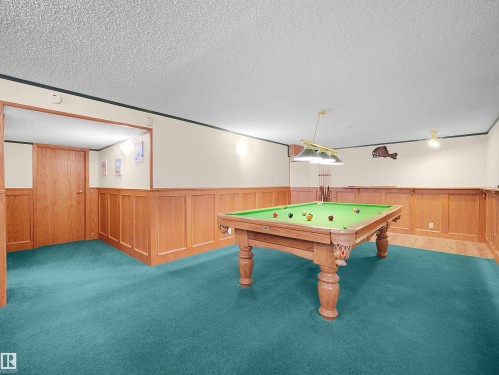 Recreation room featuring teal carpeting, wood paneling, recessed wall cut-out, and ceiling-mounted lighting fixtures - 11044 166 Avenue, Edmonton, AB - Indoor Photo Showing Other Room