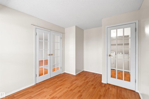 Bright interior space featuring warm wood-finish flooring, white walls, and a textured ceiling - 1116 Saddleback Road, Edmonton, AB - Indoor Photo Showing Other Room