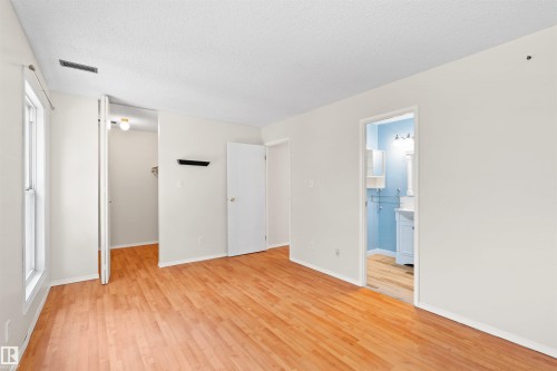 Hardwood-finish flooring extends throughout this room, featuring light-colored walls and a textured ceiling - 1116 Saddleback Road, Edmonton, AB - Indoor Photo Showing Other Room