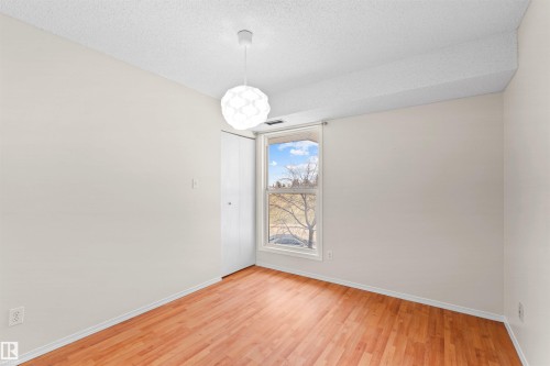 Room featuring wood-finish flooring, a contemporary pendant light fixture, and a window with a white frame - 1116 Saddleback Road, Edmonton, AB - Indoor Photo Showing Other Room