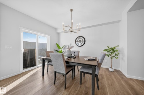 Dining area featuring wood-finish flooring, white walls, and a contemporary chandelier - 20723 24 Avenue, Edmonton, AB - Indoor Photo Showing Dining Room