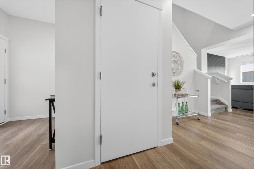 Entryway featuring wood-finish flooring, white trim, and a contemporary white door with brushed metal hardware - 20723 24 Avenue, Edmonton, AB - Indoor Photo Showing Other Room