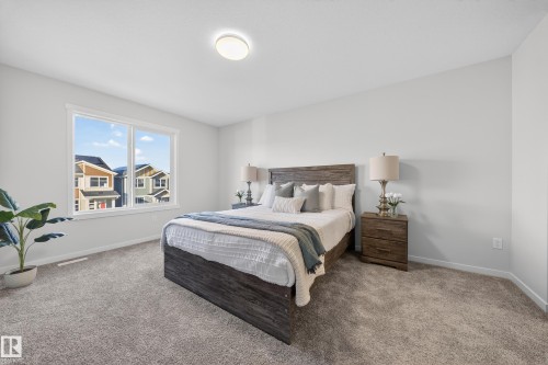 Spacious bedroom featuring light gray carpeting, a large window with white trim, and light-toned wall finishes - 20723 24 Avenue, Edmonton, AB - Indoor Photo Showing Bedroom