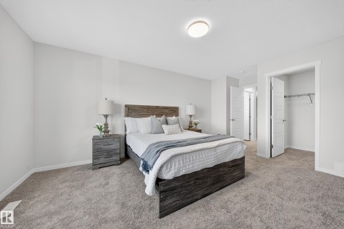 Carpeted bedroom featuring neutral wall tones, a built-in closet with shelving and hanging rod, a flush-mount ceiling light, and white trim - 20723 24 Avenue, Edmonton, AB - Indoor Photo Showing Bedroom