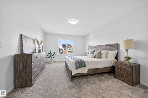 Carpeted bedroom featuring neutral wall tones, a large window, and a ceiling-mounted light fixture - 20723 24 Avenue, Edmonton, AB - Indoor Photo Showing Bedroom