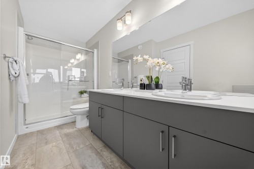 Bathroom featuring a dual-sink vanity with gray cabinetry and white countertops, a large mirror, and a walk-in shower with a sliding glass door - 20723 24 Avenue, Edmonton, AB - Indoor Photo Showing Bathroom