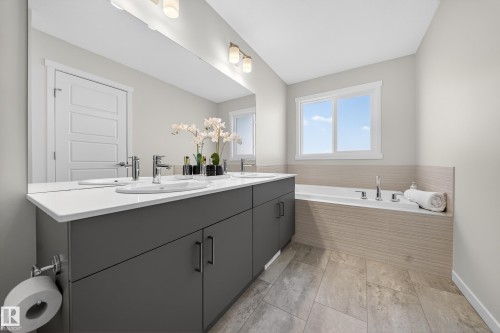 Dual sink vanity with dark grey cabinetry, white countertops, and chrome fixtures - 20723 24 Avenue, Edmonton, AB - Indoor Photo Showing Bathroom