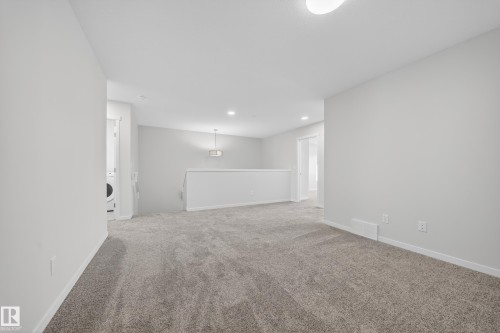 Carpeted landing area featuring a white railing, a built-in washer and dryer unit, recessed lighting, and a pendant light fixture - 20723 24 Avenue, Edmonton, AB - Indoor Photo Showing Other Room