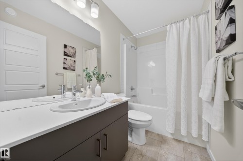 Bathroom featuring a built-in vanity with dual sinks, white countertop, and dark cabinetry - 20723 24 Avenue, Edmonton, AB - Indoor Photo Showing Bathroom