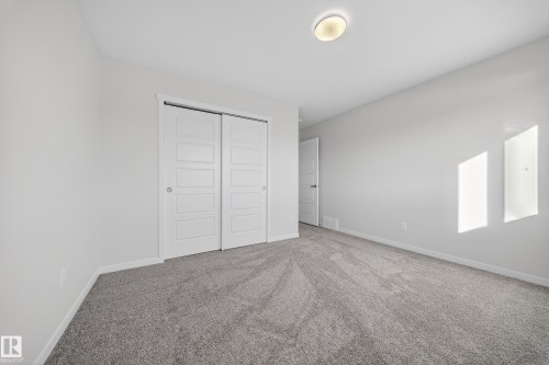 Gray carpeted room featuring white walls and a pair of white sliding closet doors - 20723 24 Avenue, Edmonton, AB - Indoor Photo Showing Other Room