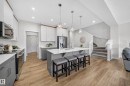 Open-concept kitchen featuring an island with built-in seating, stainless steel appliances, and two-tone cabinetry - 20723 24 Avenue, Edmonton, AB  - Indoor Photo Showing Kitchen With Upgraded Kitchen 
