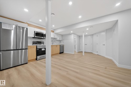 Contemporary kitchen space featuring stainless steel appliances, two-tone cabinetry, and wood-finish flooring - 20723 24 Avenue, Edmonton, AB - Indoor Photo Showing Kitchen