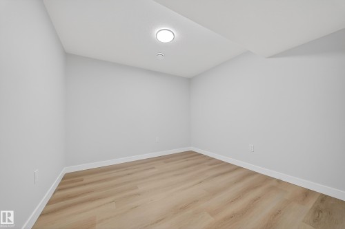Interior room featuring wood-finish flooring, light gray wall paint, white trim, and a ceiling-mounted light fixture - 20723 24 Avenue, Edmonton, AB - Indoor Photo Showing Other Room