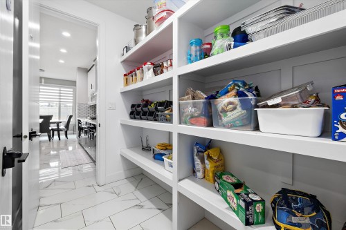 Walk-in pantry featuring extensive built-in shelving, white finishes, and a durable tile flooring - 714 Ebbers Place, Edmonton, AB - Indoor With Storage