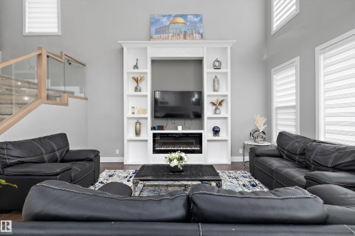 Living area featuring a floor-to-ceiling built-in entertainment unit with shelving and an electric fireplace - 714 Ebbers Place, Edmonton, AB - Indoor Photo Showing Living Room