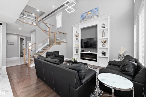Two-story living area with a vaulted ceiling and an integrated entertainment center featuring an electric fireplace - 714 Ebbers Place, Edmonton, AB - Indoor Photo Showing Living Room