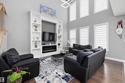 Living area featuring a floor-to-ceiling custom built-in entertainment unit with shelving, an integrated electric fireplace, and a television recess - 714 Ebbers Place, Edmonton, AB - Indoor Photo Showing Living Room
