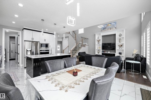Open-concept main level featuring a white kitchen with black island, stainless steel appliances, and pendant lighting - 714 Ebbers Place, Edmonton, AB - Indoor Photo Showing Dining Room