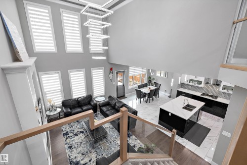 Two-story living area with a tiered chandelier, multiple vertical windows, and a built-in media cabinet - 714 Ebbers Place, Edmonton, AB - Indoor Photo Showing Other Room