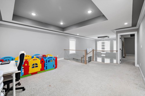 Spacious open room featuring light-colored carpeting, multiple recessed ceiling lights, and tray ceiling details - 714 Ebbers Place, Edmonton, AB - Indoor