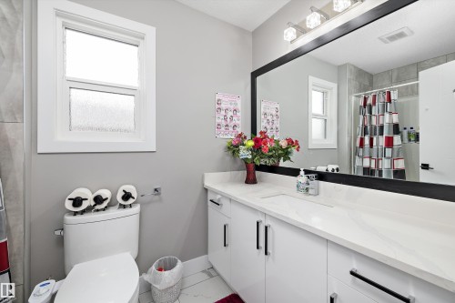 Contemporary bathroom featuring a white vanity with integrated sink, a large framed mirror, and an overhead vanity light fixture - 714 Ebbers Place, Edmonton, AB - Indoor Photo Showing Bathroom