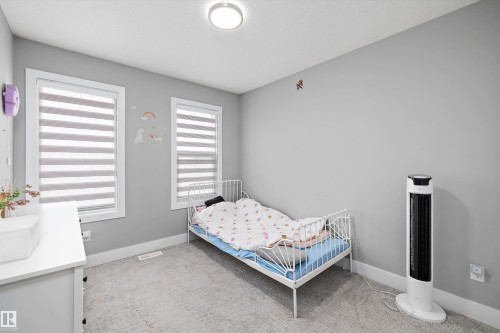 Room featuring two windows with horizontal blinds, light gray walls, and carpet flooring - 714 Ebbers Place, Edmonton, AB - Indoor Photo Showing Bedroom
